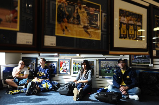 From left, Michigan junior Courtney Lantzer, Ohio, junior Matt Simpson, Lansing, sophomore Gabby Gutierrez, Woodhaven, and alumni Jeffrey Groom, Utica, sit on the floor as they wait in line for a chance to meet Desmond Howard during an autograph signing at the M Den on Friday. Melanie Maxwell I AnnArbor.com